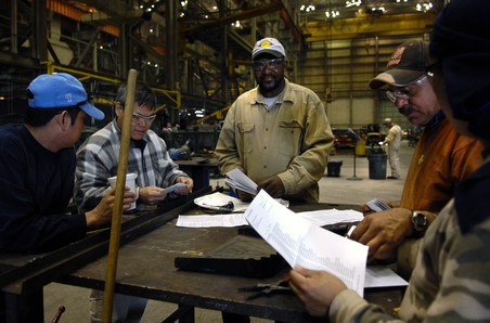 Workers at Force Protection Industries Inc., look over paperwork