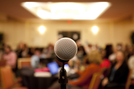 Image of a microphone in a room full of people